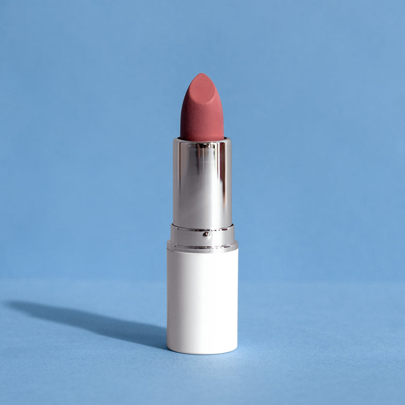 Rouge à lèvres rose dans un étui argenté et blanc sur fond bleu, photo produit