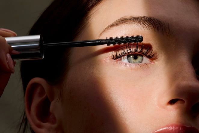 Frau trägt Mascara auf ihre oberen Wimpern auf, Nahaufnahme des Auges