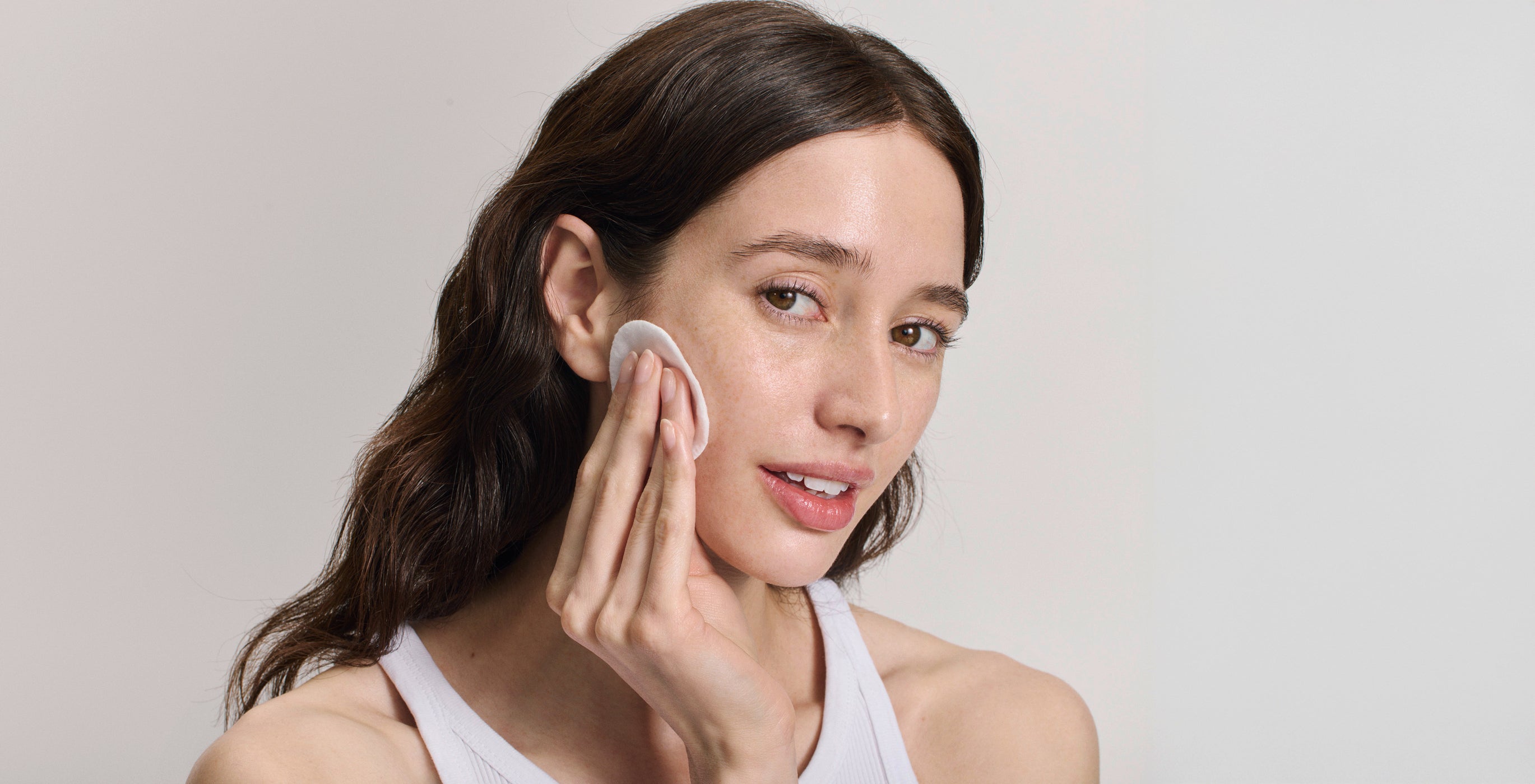 Femme nettoie délicatement son visage avec coton – routine de soin quotidienne pour une peau éclatante
