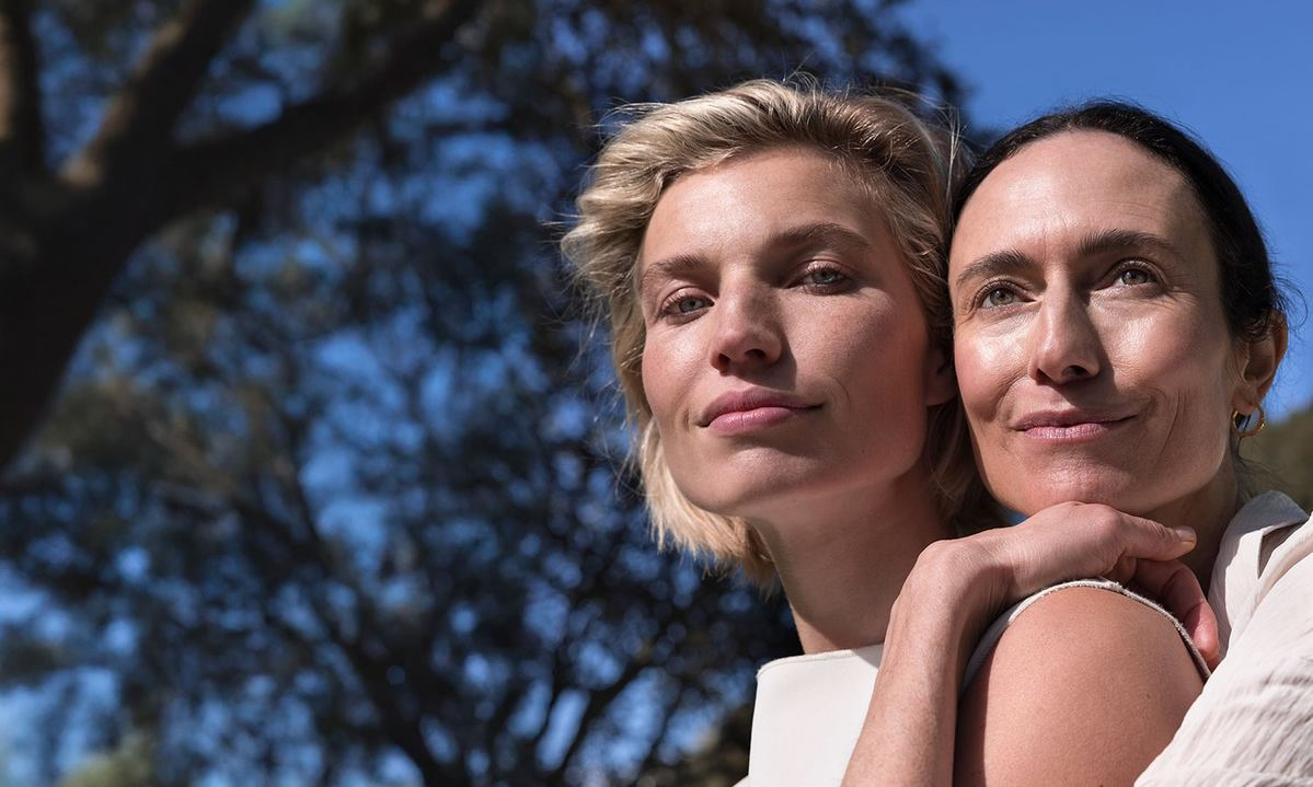 Deux femmes au soleil, l'une enlace l'autre, look naturel en extérieur