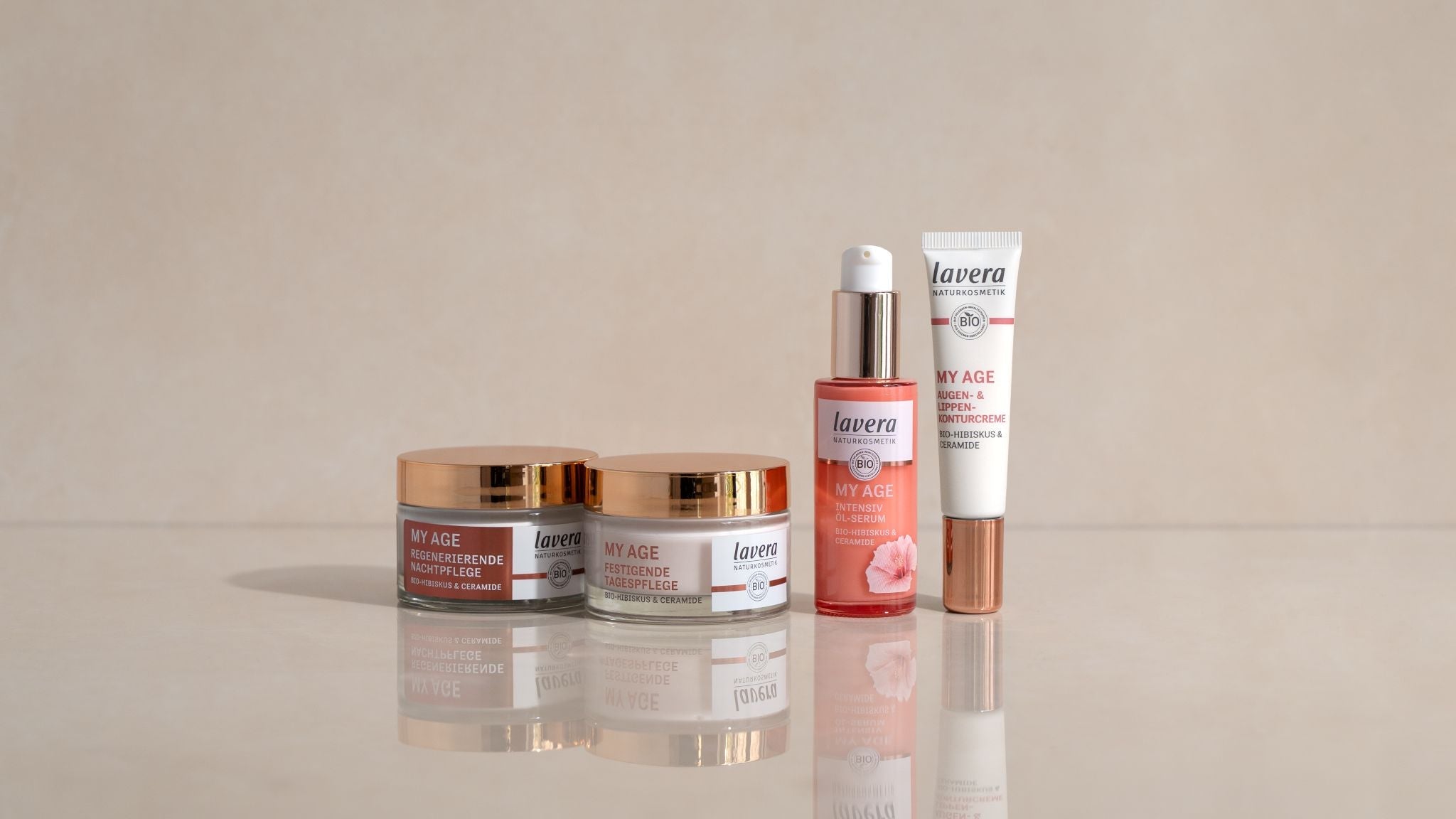 lavera My Age produits de soin anti-âge avec hibiscus bio et céramides : crème nuit, crème jour, sérum huile et crème contour yeux & lèvres, disposés de manière décorative sur fond clair