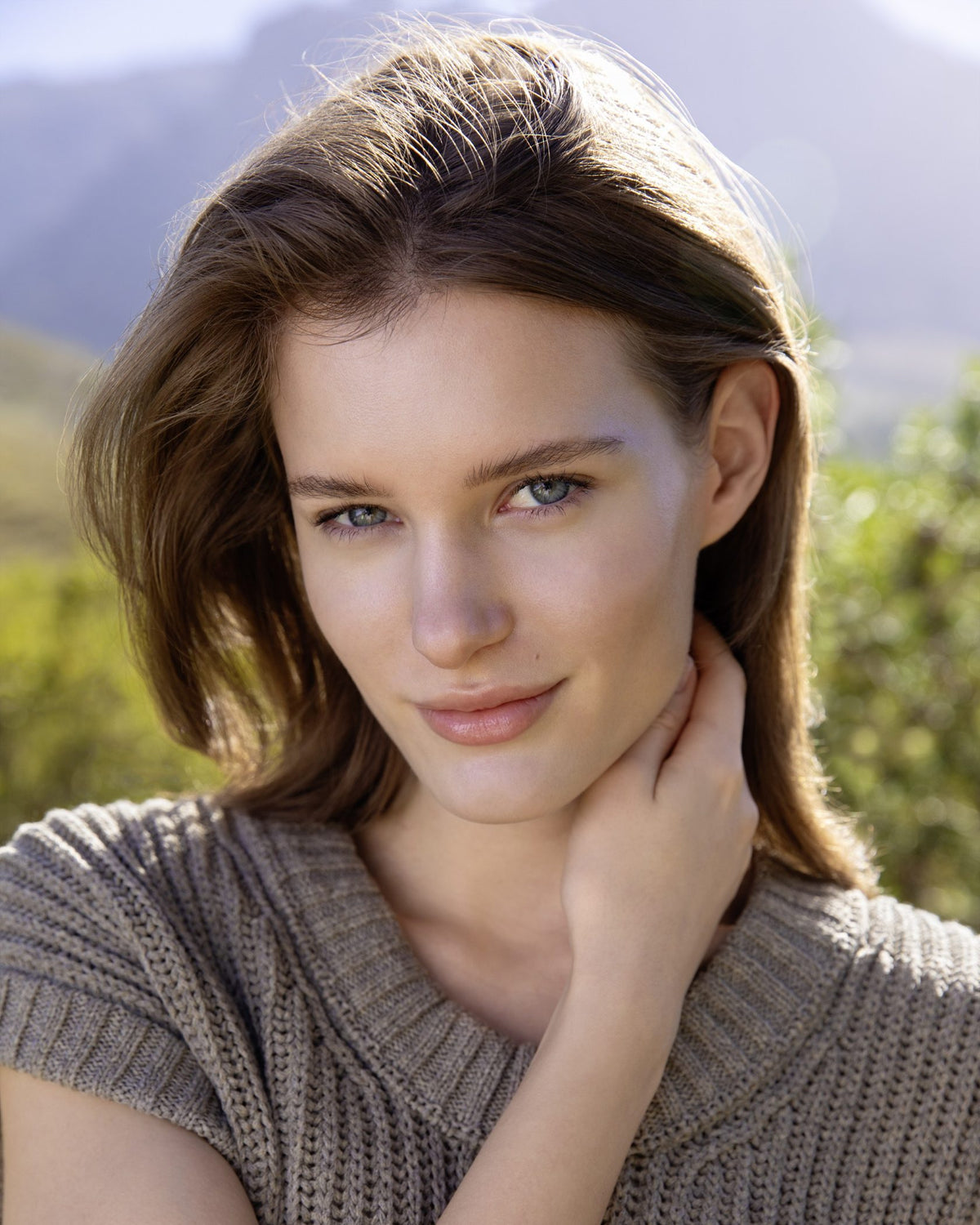 Brown-haired woman outdoors with a natural look against a mountain backdrop