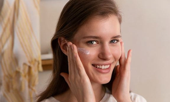 Femme applique fluide anti-UV sur la joue en souriant