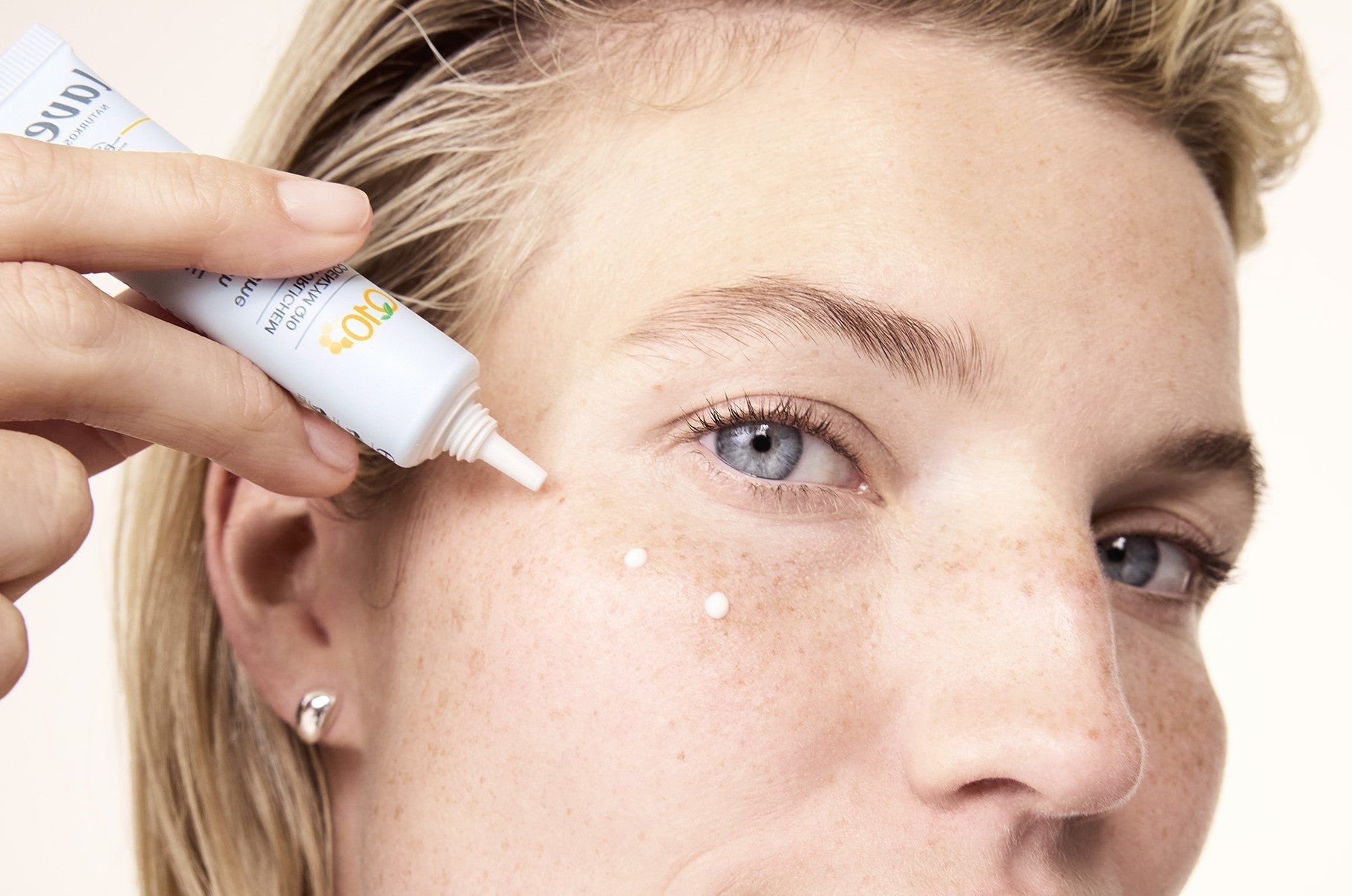 Femme applique crème pour les yeux sur le visage par points