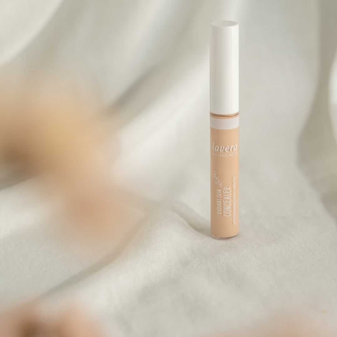 A lavera Liquid Skin Concealer stands on light-colored fabric against a softly draped background with blurred beige accents.
