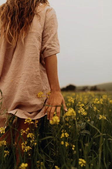 Femme de dos dans un champ avec des fleurs jaunes