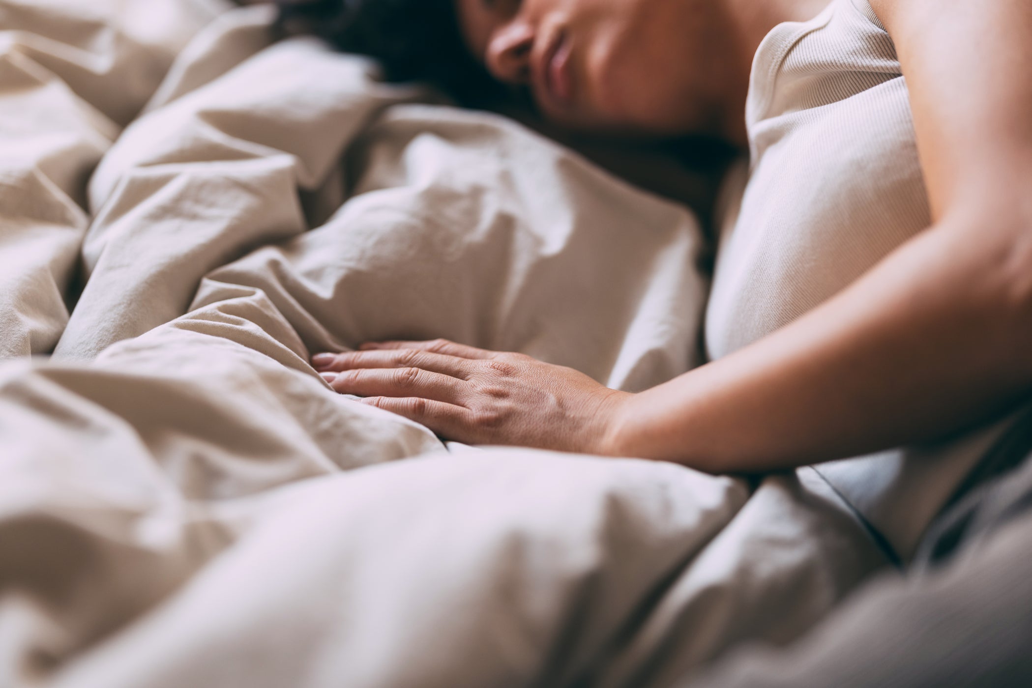 Femme allongée sur un lit avec housse de couette grise
