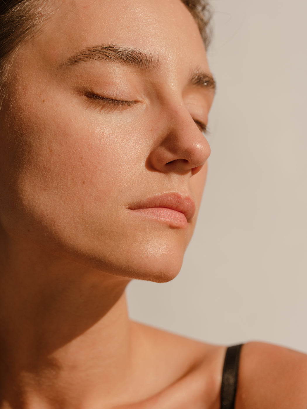Femme yeux fermés à la lumière du soleil et peau naturellement radieuse – expression faciale détendue