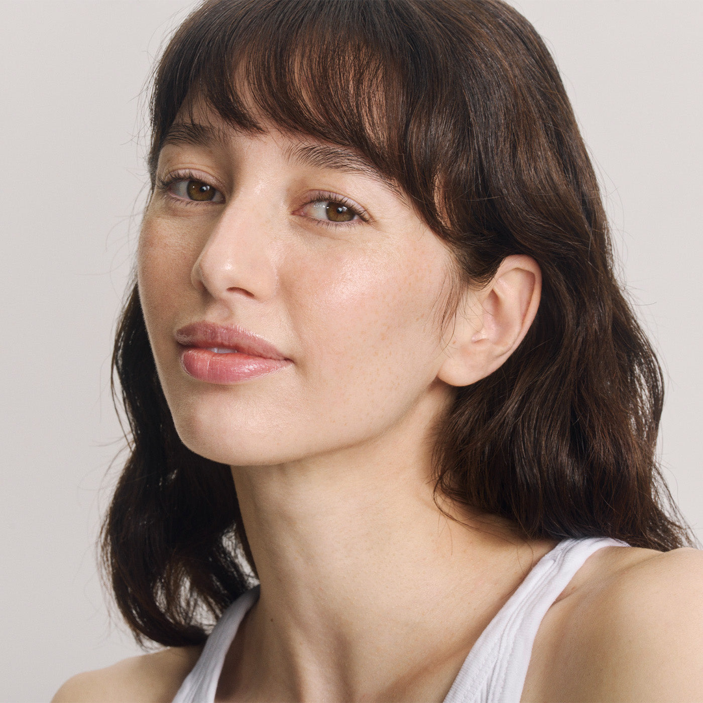 Portrait de jeune femme aux cheveux bruns, frange et yeux bruns