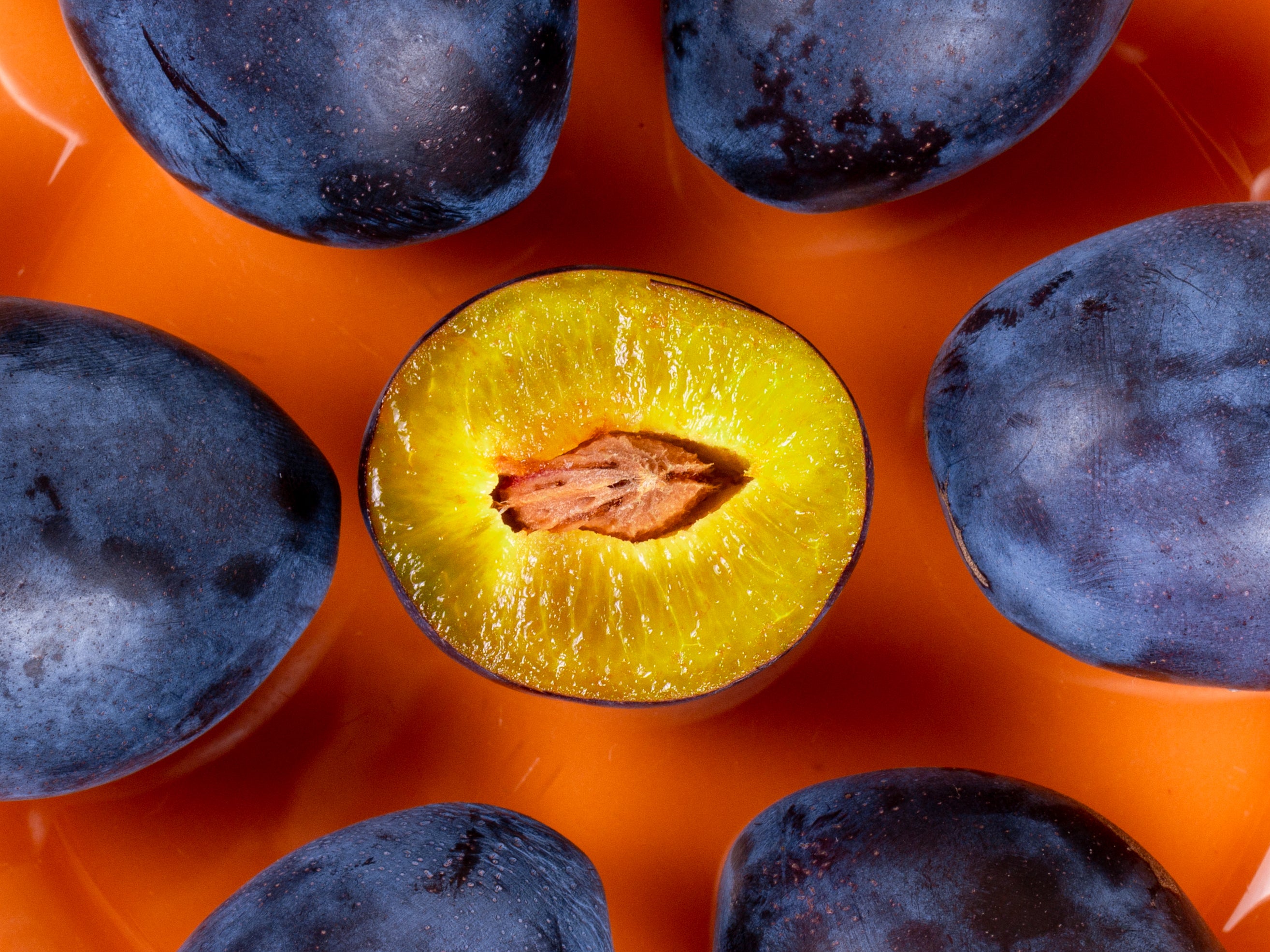 aufgeschnittene Pflaume auf orangenem Untergrund