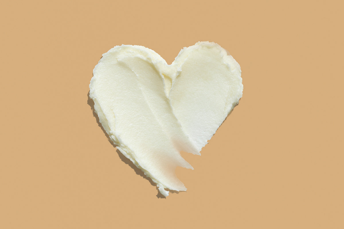 Texture de crème en forme de cœur sur fond orange clair