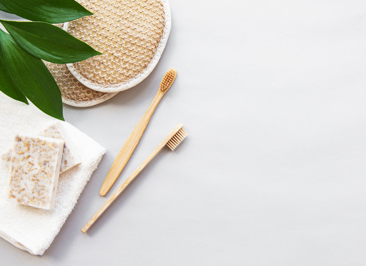Accessoires de soin comme éponge, brosse à dents et savon côte à côte sur fond blanc