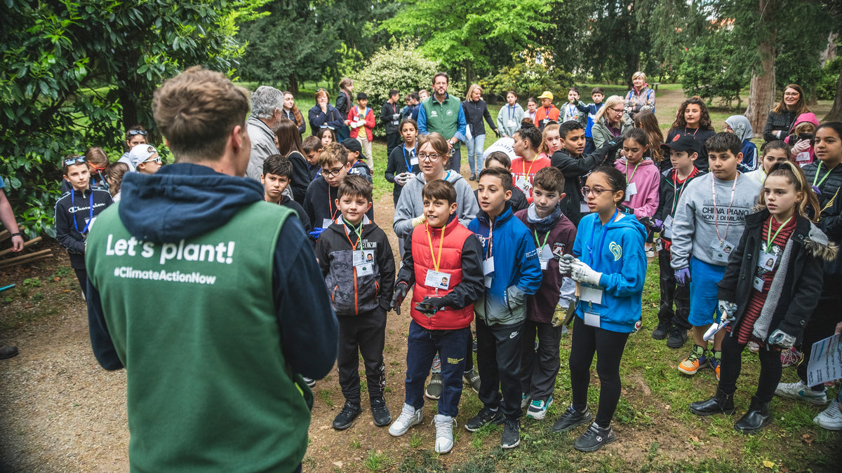 Jeune homme en gilet vert devant un groupe d'enfants en plein air