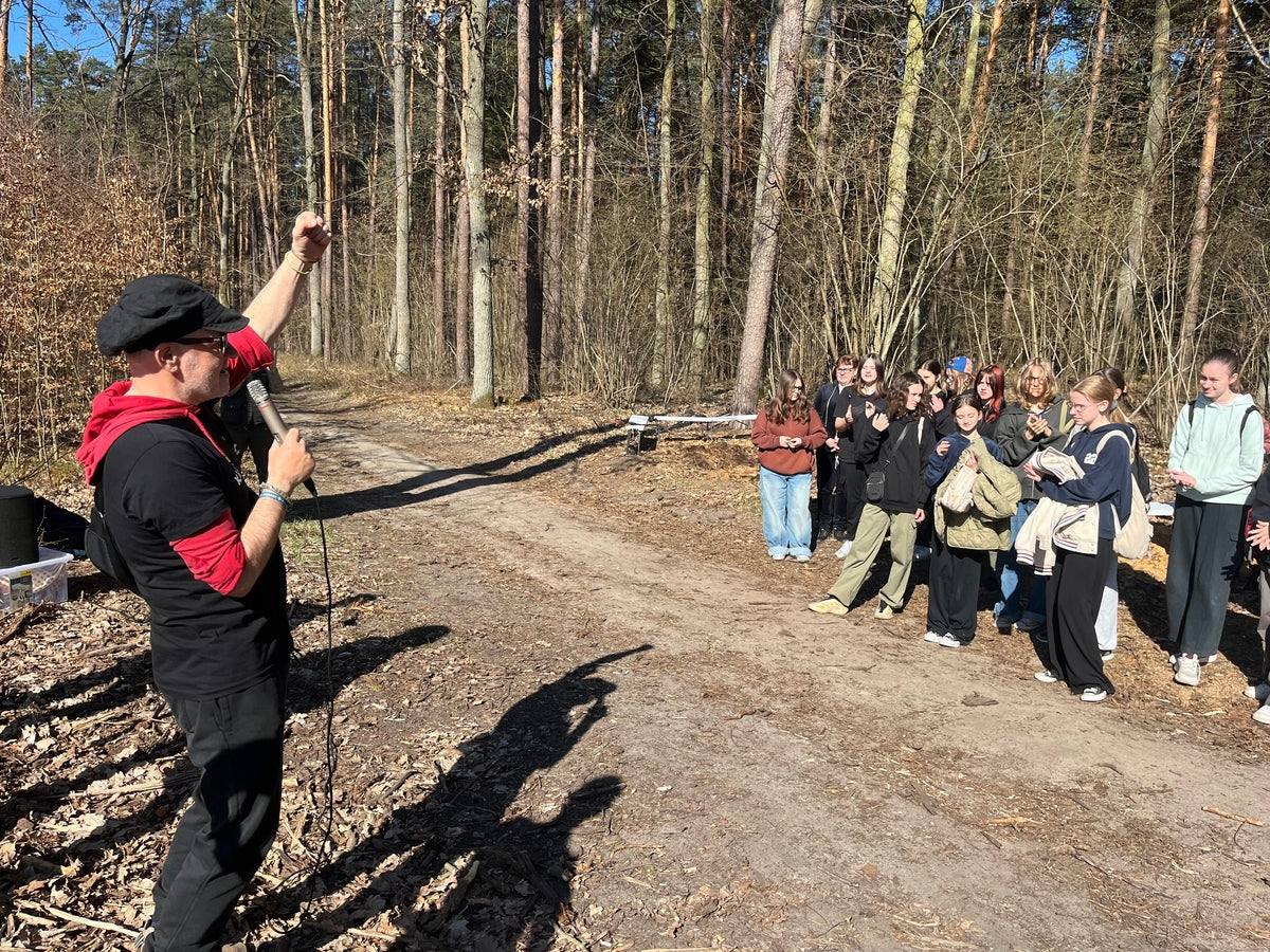 Homme avec microphone devant un groupe d'enfants et adolescents, poing levé
