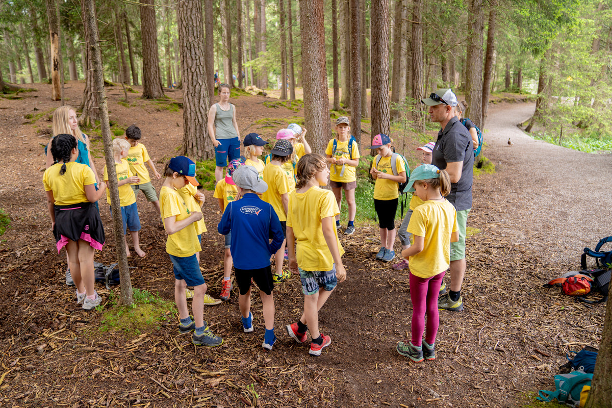 Groupe de deux adultes et d'enfants debout dans la forêt entre de grands arbres