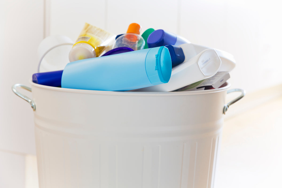 Différents emballages cosmétiques dans une poubelle blanche