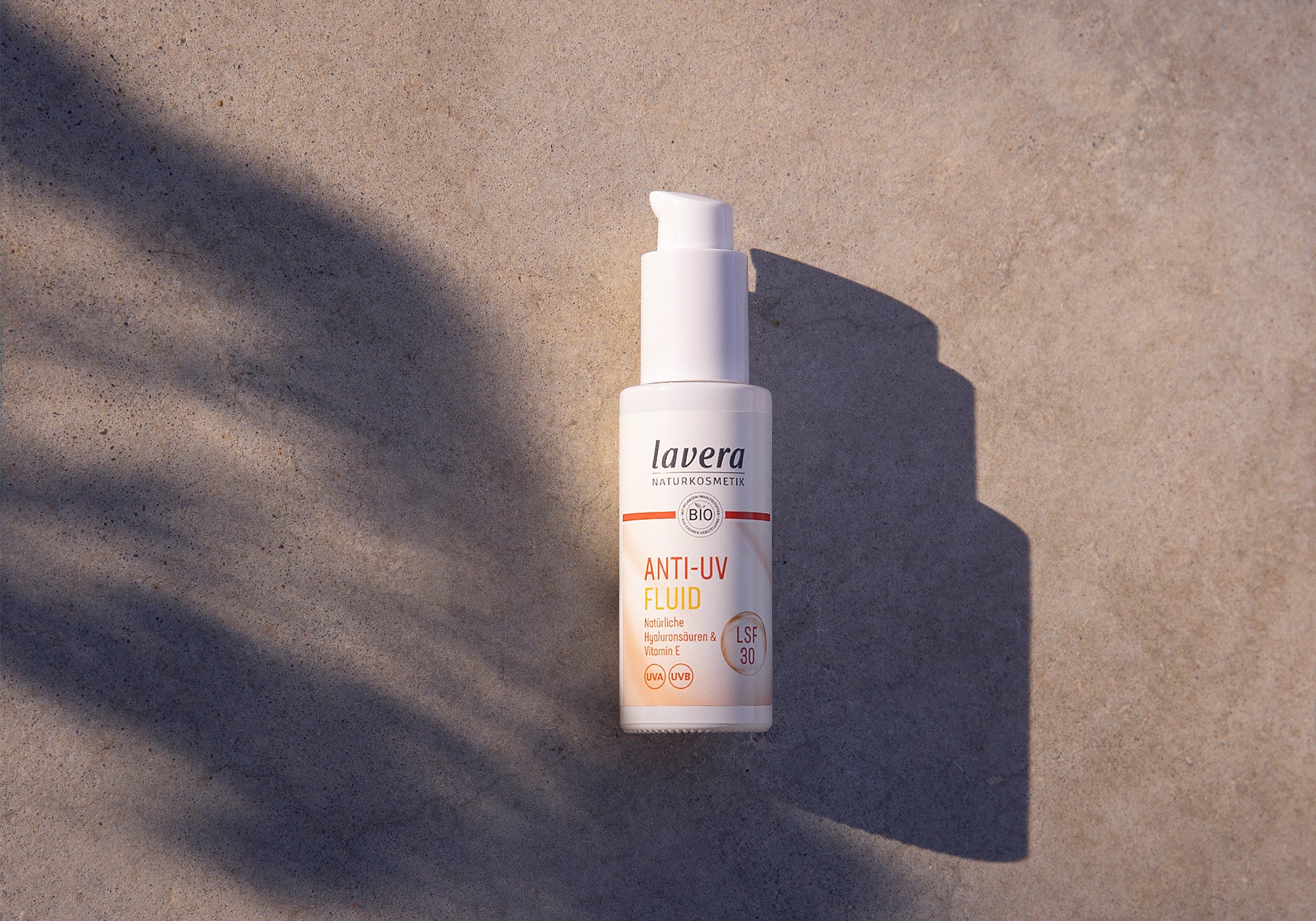 Anti UV Fluid sur fond gris, sur lequel brille le soleil
