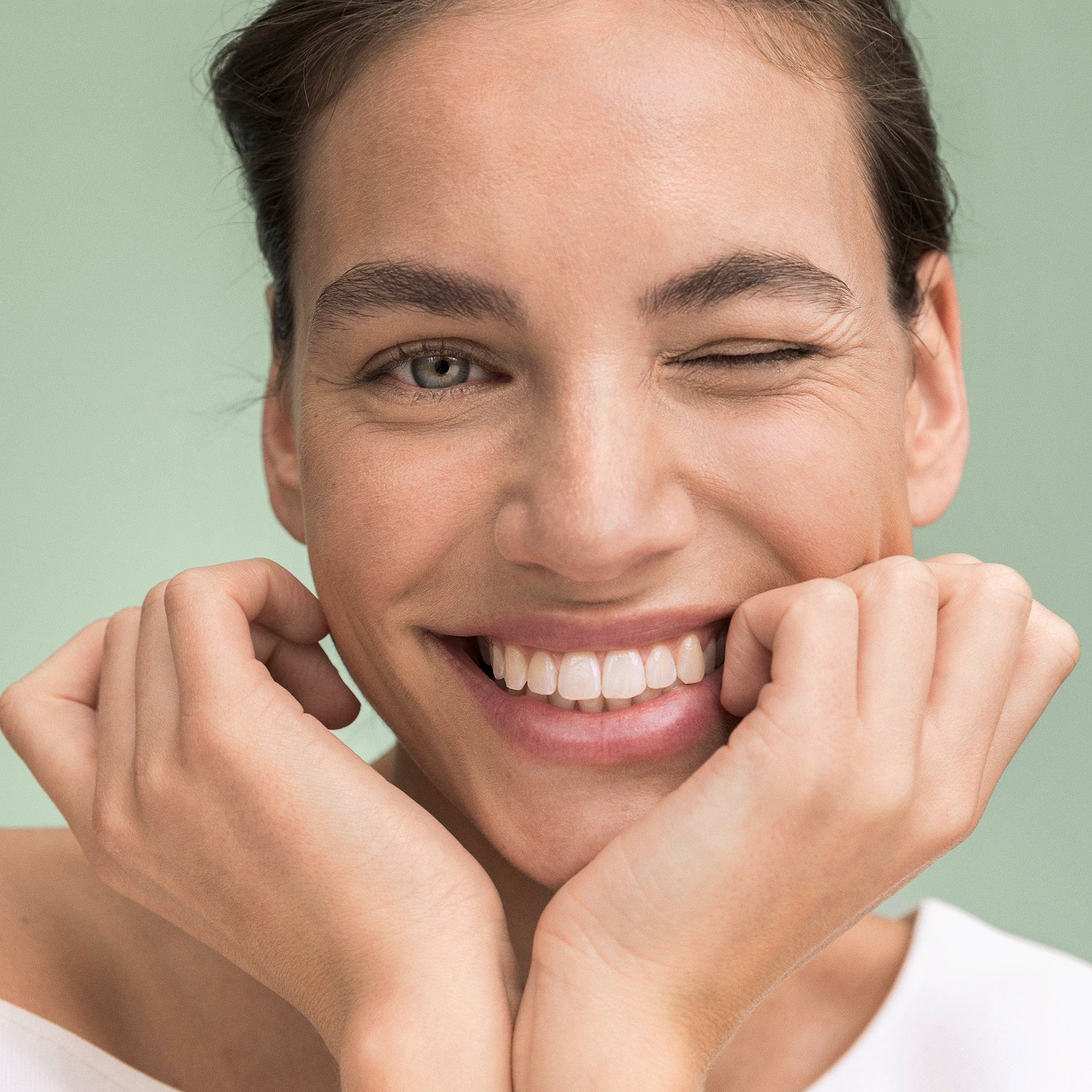 Femme tenant la tête dans les mains en souriant