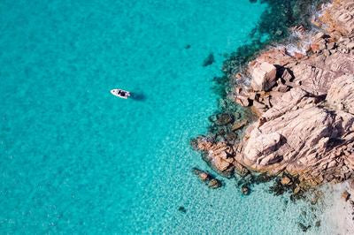 Bateau dans une mer turquoise près d'une côte rocheuse vue d'en haut