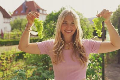 Femme sourit et tient raisins verts en l'air
