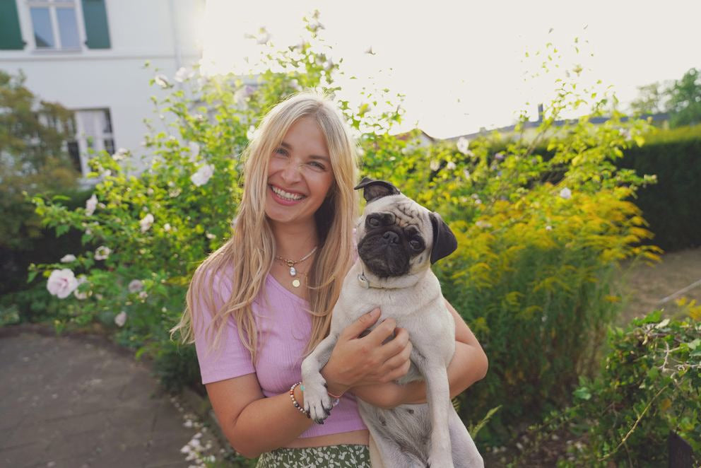 Femme blonde souriante tenant un carlin dans ses bras