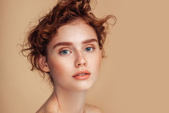 Portrait d'une femme rousse avec taches de rousseur sur fond beige