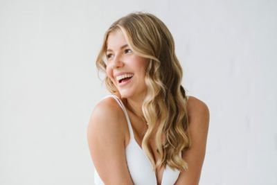 Femme souriante aux longs cheveux blonds sur fond clair