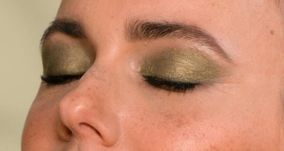 Gros plan de la moitié centrale du visage d'une femme avec maquillage des yeux vert foncé en vue latérale et yeux fermés