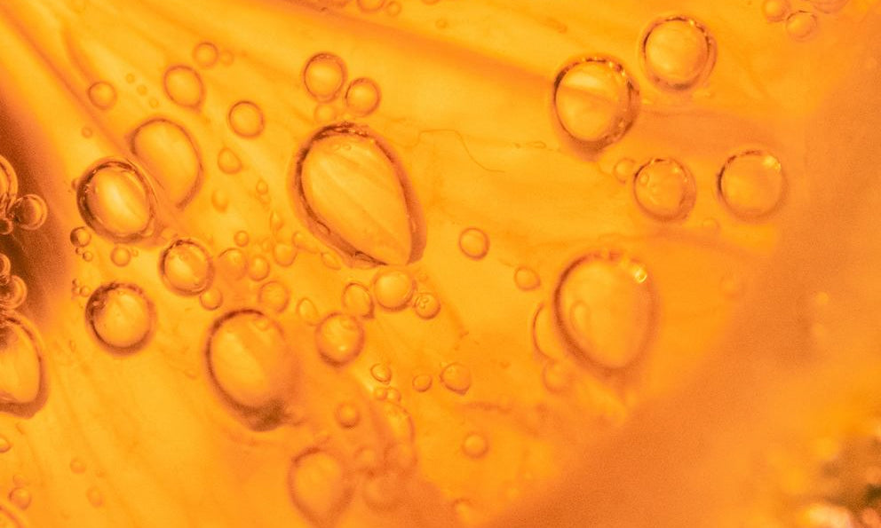 Makro: orangefarbene Öltextur mit Luftblasen, Serum-Hintergrund